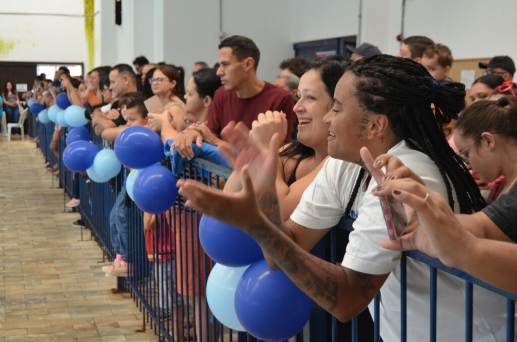 Famílias acompanham e aplaudem uma atividade de natação.