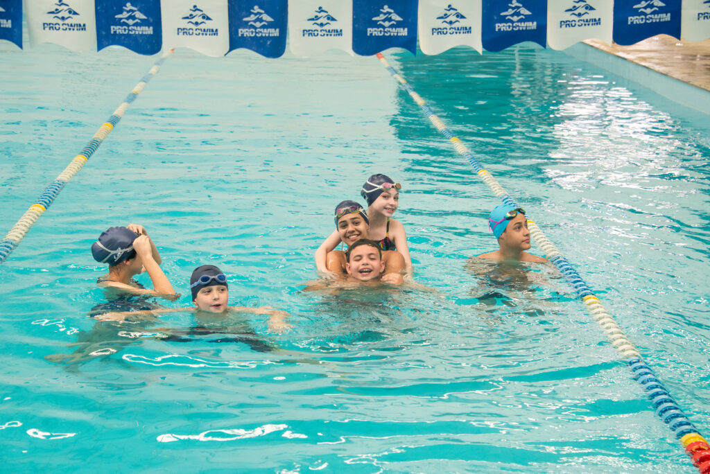 Grupo de crianças brinca e se diverte na piscina após uma atividade de natação.